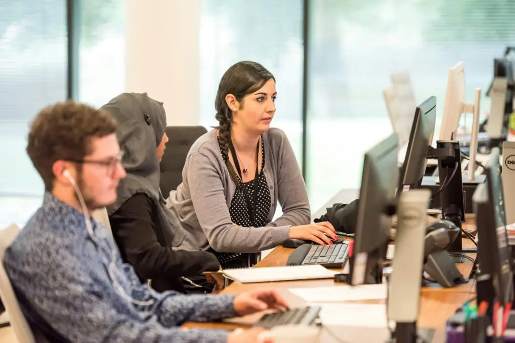 Customer service staffing; diverse team of support representatives working at computers in a modern open-plan office.