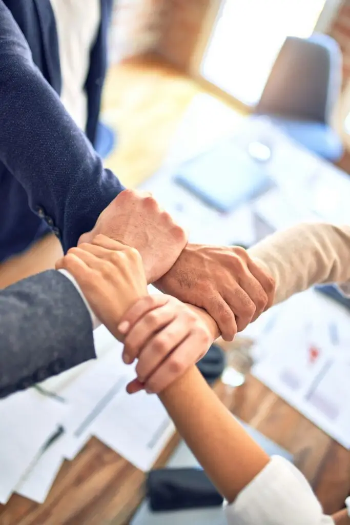 Close-up of four diverse hands linked, representing a collaborative staffing approach that results in quicker placements and quality service staffing solutions.